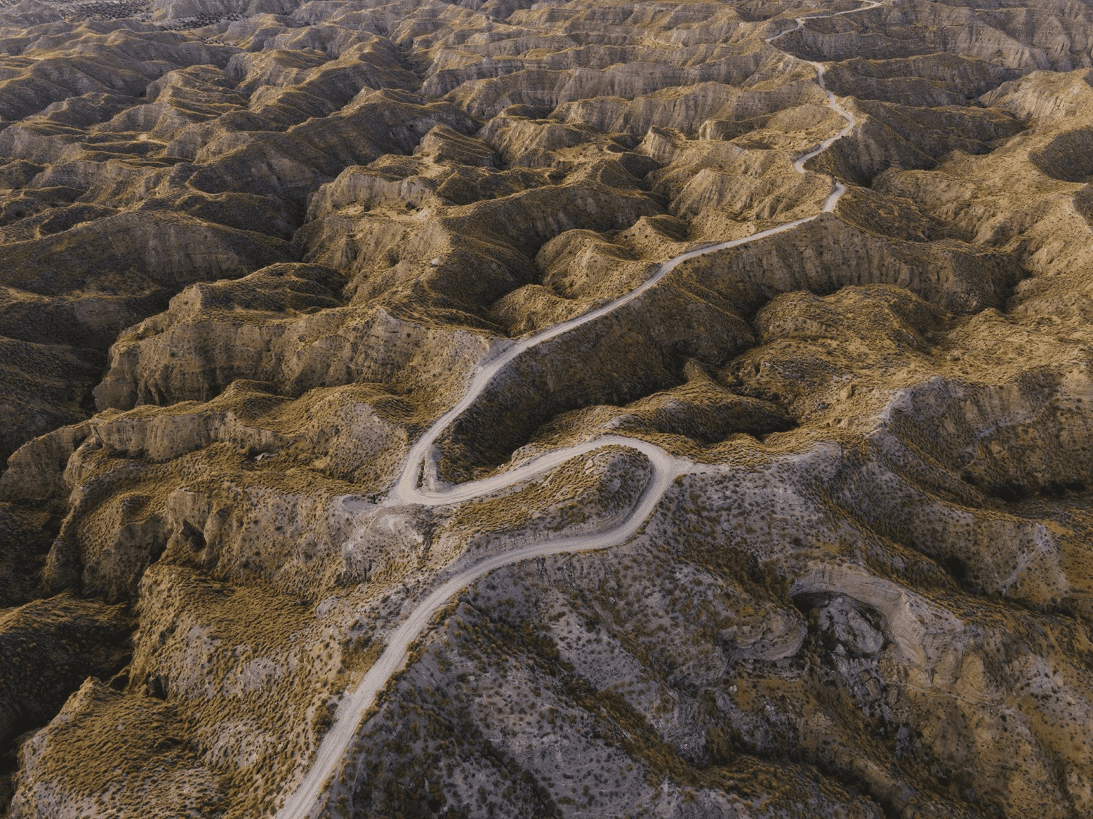 Gravel rider crossing the Andalucían désert with Pico Veleta in the background during Badlands