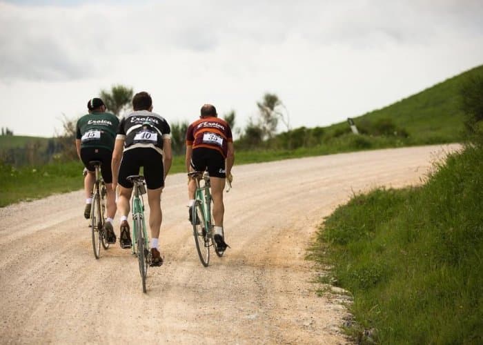 Vintage cyclists on steel bikes riding the white gravel roads of Chianti during L'Eroica in Tuscany