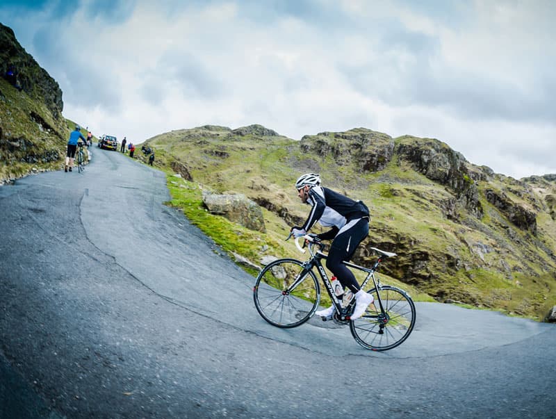 Cyclists grinding up the steep Hardknott Pass during the Fred Whitton Challenge in the Lake District