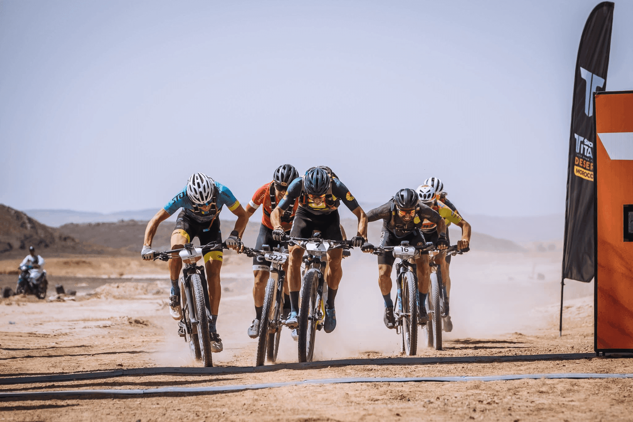MTB riders crossing sand dunes and Atlas Mountains trails during Titan Desert Morocco