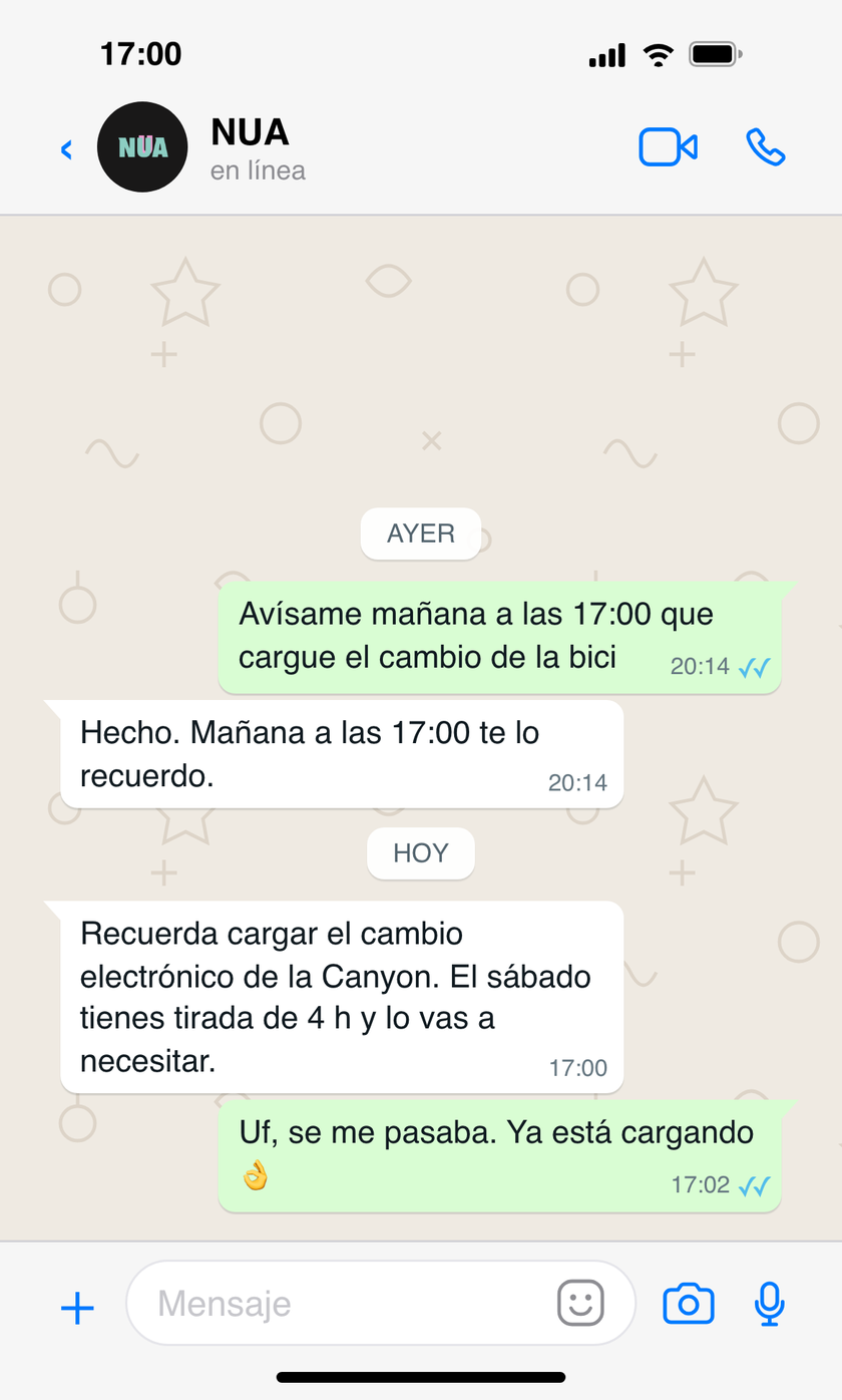 Conversación en WhatsApp donde el atleta pide a NUA un recordatorio para cargar el cambio electrónico de la bici, y NUA se lo recuerda al día siguiente a la hora acordada